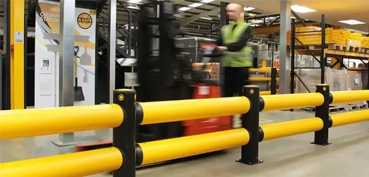 Operator on forklift travelling past barrier system in warehouse